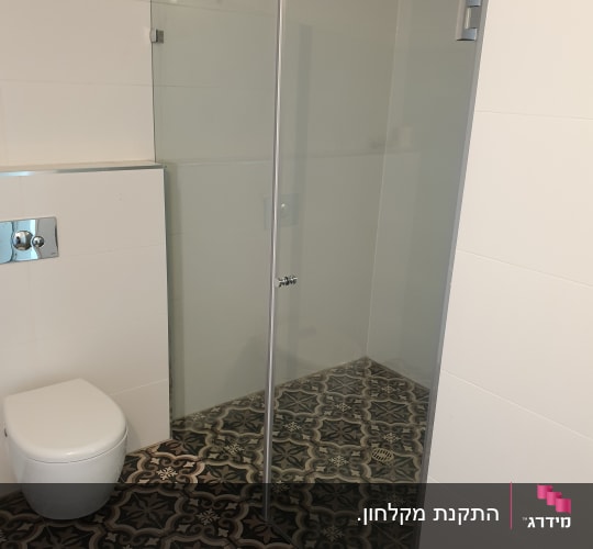 מקלחון זכוכית חזיתי מותקן בחדר רחצה עם ריצוף מצויר